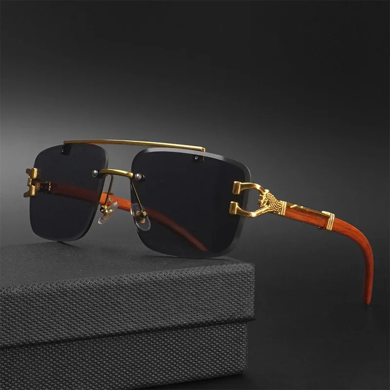 Gafas de sol de estilo lujoso y cuadrado, sin montura, con lentes polarizadas oscuras. Tienen un doble puente superior y detalles metálicos en color dorado. Las patillas presentan un acabado veteado que imita madera marrón claro con un elaborado adorno metálico dorado. Se apoyan sobre una caja negra texturizada.